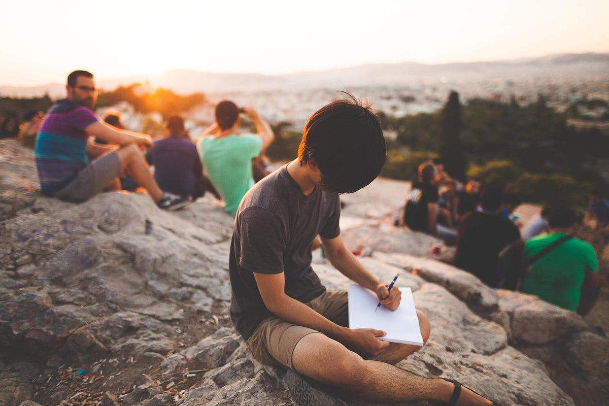 Friends sitting together on a hilltop at sunset